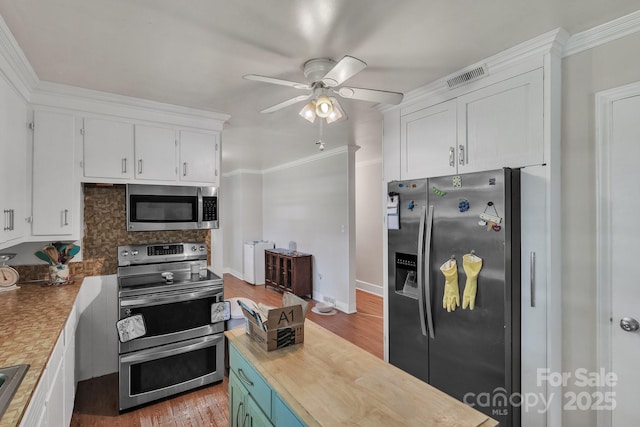 2008 Kimway Dr, Matthews, NC 28105 - kitchen with appliances with stainless steel finishes, white cabinets, ceiling fan, wood finished floors, and ornamental molding