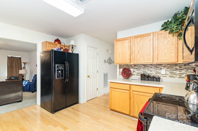 6619 Bittinger Ct, Charlotte, NC 28216 - kitchen with black fridge with ice dispenser, range with electric stovetop, light wood finished floors, light countertops, and light brown cabinets
