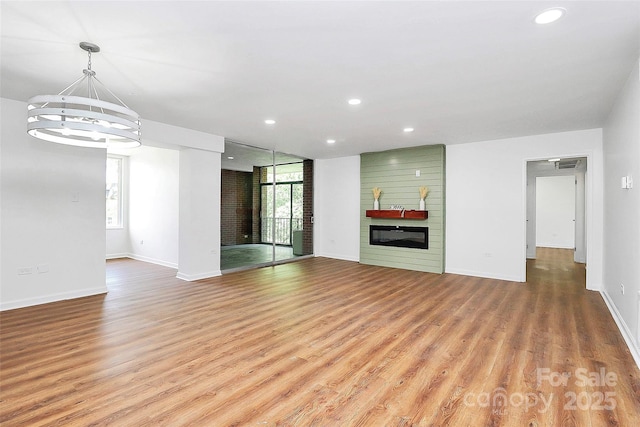 1300 Queens Rd Unit 405, Charlotte, NC 28207 - unfurnished living room featuring a large fireplace, a chandelier, light wood finished floors, and recessed lighting