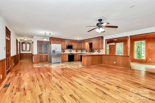 3311 Camden Rd, Marshville, NC 28103 - kitchen featuring stainless steel fridge, black microwave, brown cabinetry, light wood-style floors, and wooden walls