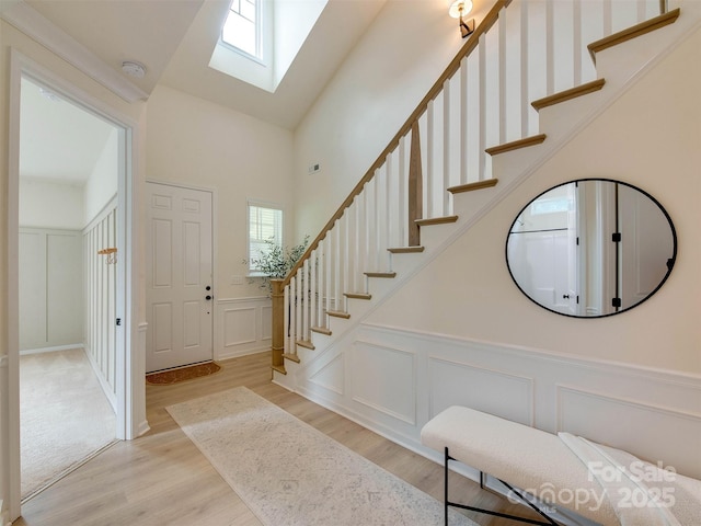 16108 Langston Dr, Charlotte, NC 28278 - foyer featuring a skylight, a decorative wall, stairway, light wood-style flooring, and wainscoting