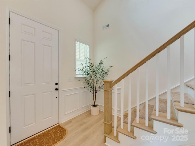 16108 Langston Dr, Charlotte, NC 28278 - foyer with light wood finished floors, stairs, wainscoting, a high ceiling, and a decorative wall