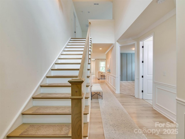 16108 Langston Dr, Charlotte, NC 28278 - stairs featuring a decorative wall, wood finished floors, a high ceiling, and wainscoting