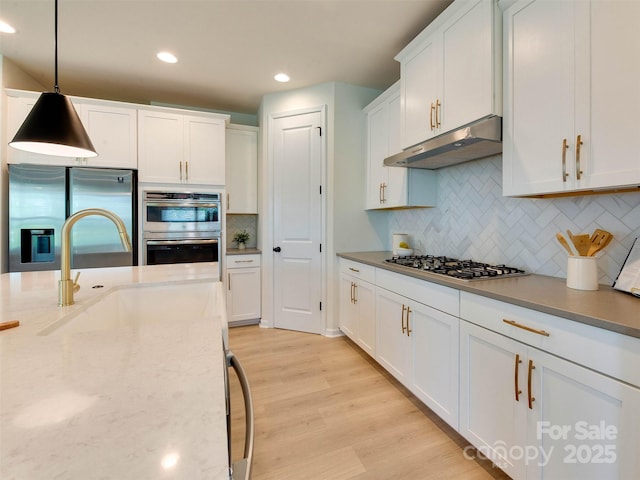 16108 Langston Dr, Charlotte, NC 28278 - kitchen with stainless steel appliances, under cabinet range hood, white cabinetry, light wood-type flooring, and tasteful backsplash