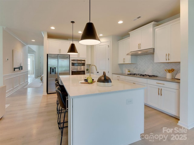 16108 Langston Dr, Charlotte, NC 28278 - kitchen with stainless steel appliances, under cabinet range hood, light wood-style floors, a breakfast bar area, and recessed lighting