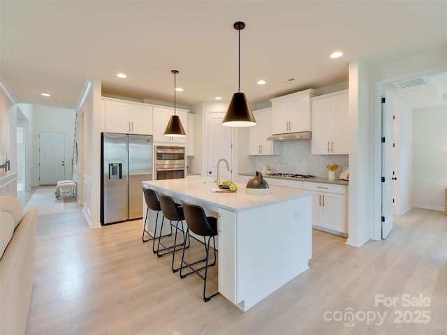 16108 Langston Dr, Charlotte, NC 28278 - kitchen with stainless steel appliances, under cabinet range hood, backsplash, light wood-style floors, and a breakfast bar