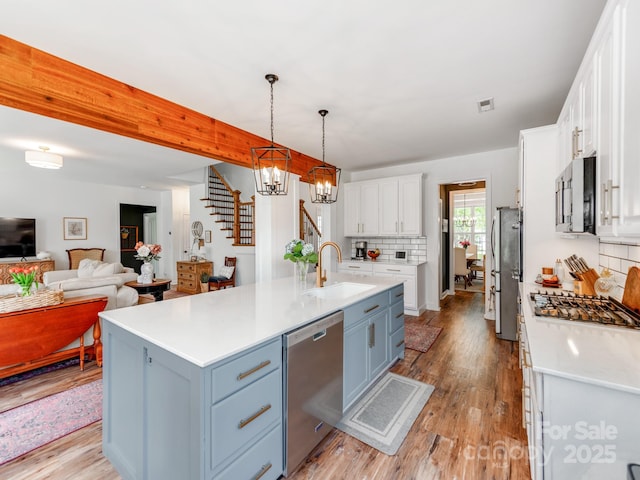 1605 Ambergate Dr, Waxhaw, NC 28173 - kitchen with stainless steel appliances, white cabinets, tasteful backsplash, light countertops, and light wood-type flooring