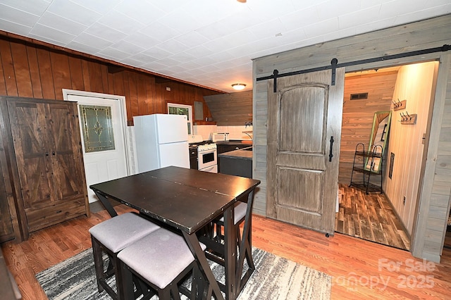 3430 Rose Creek Rd, Morganton, NC 28655 - dining space featuring a barn door, wood walls, and light wood finished floors