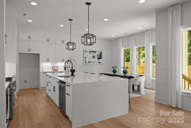3953 Plainview Rd, Charlotte, NC 28208 - kitchen featuring white cabinets, light wood-type flooring, recessed lighting, a center island with sink, and stainless steel appliances