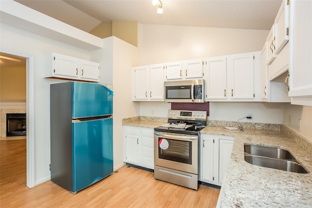 828 Saint Andrews Pl, Concord, NC 28025 - kitchen with stainless steel appliances, lofted ceiling, white cabinetry, light wood-type flooring, and light stone countertops