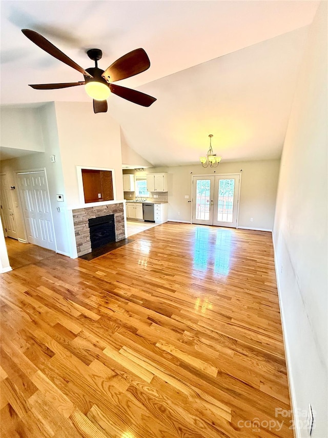 4351 Grover Pl, Granite Falls, NC 28630 - unfurnished living room with light wood finished floors, vaulted ceiling, a chandelier, a stone fireplace, and a ceiling fan
