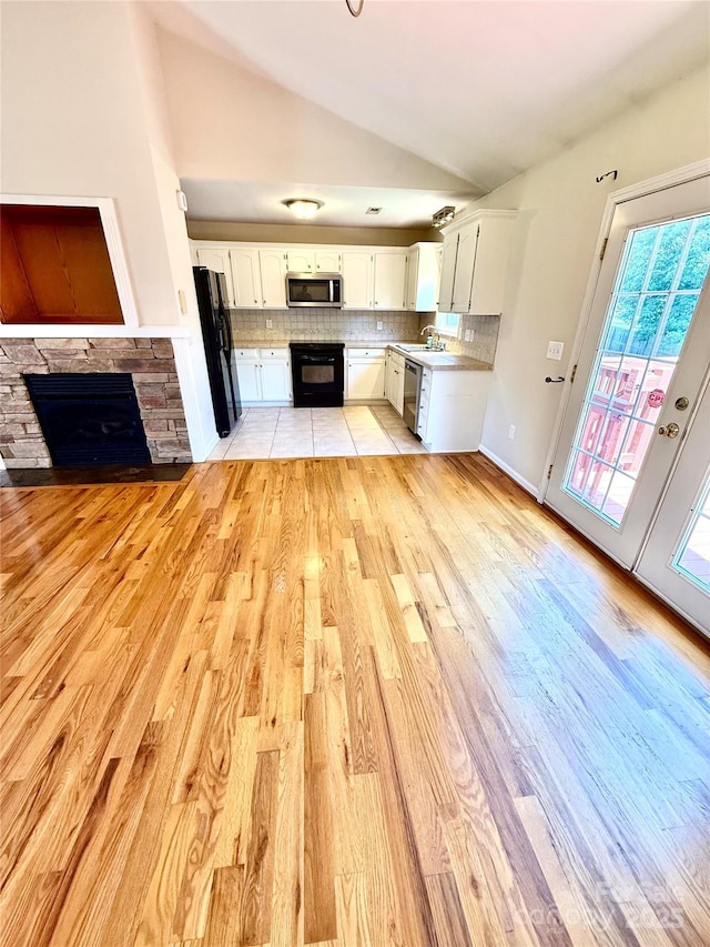 4351 Grover Pl, Granite Falls, NC 28630 - unfurnished living room featuring vaulted ceiling, a stone fireplace, and light wood-style floors
