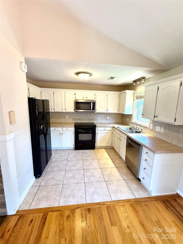 4351 Grover Pl, Granite Falls, NC 28630 - kitchen featuring black appliances, vaulted ceiling, decorative backsplash, white cabinets, and light wood-style floors