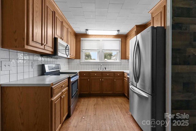 435 Stirewalt Rd, China Grove, NC 28023 - kitchen featuring stainless steel appliances, brown cabinets, light wood-style flooring, tasteful backsplash, and light countertops