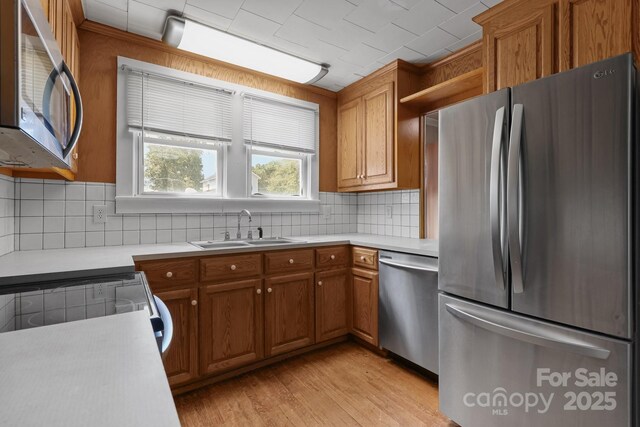 435 Stirewalt Rd, China Grove, NC 28023 - kitchen with appliances with stainless steel finishes, brown cabinets, light countertops, light wood finished floors, and decorative backsplash