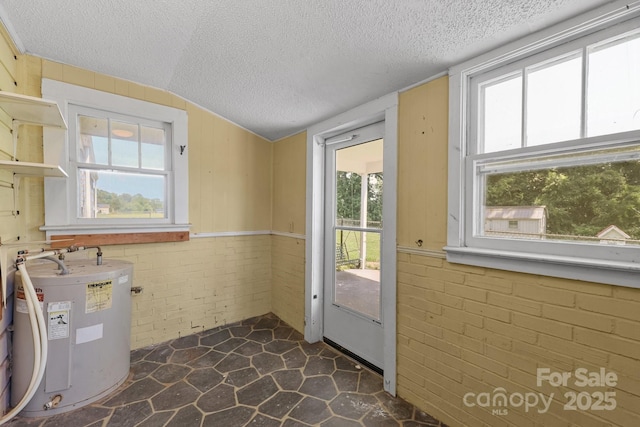 435 Stirewalt Rd, China Grove, NC 28023 - doorway to outside featuring water heater, a textured ceiling, brick wall, vaulted ceiling, and stone flooring