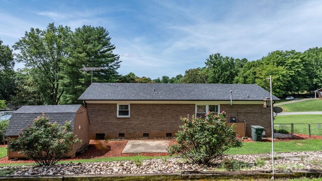 1040 Stagecoach Trl, Lenoir, NC 28645 - rear view of house with crawl space, a patio area, a storage shed, a shingled roof, and brick siding