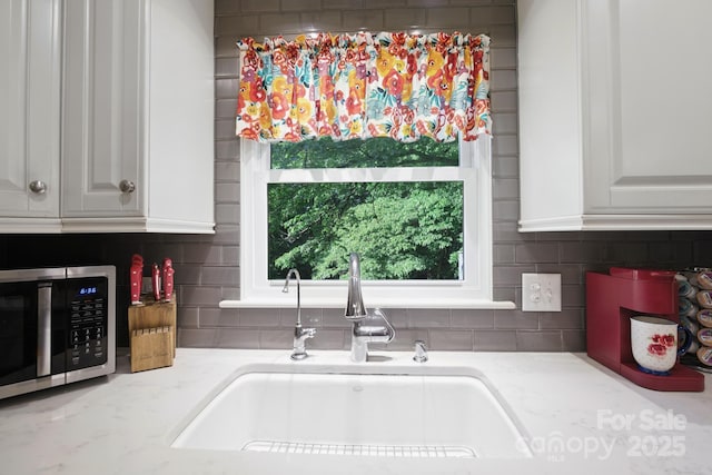 310 25th Ave NW, Hickory, NC 28601 - kitchen featuring stainless steel microwave, light stone counters, white cabinets, and decorative backsplash