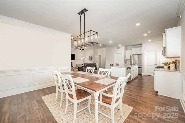 7739 Village Pkwy, Locust, NC 28097 - dining area with dark wood-style flooring, ornamental molding, recessed lighting, a chandelier, and wainscoting