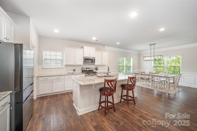 7739 Village Pkwy, Locust, NC 28097 - kitchen featuring appliances with stainless steel finishes, dark wood-type flooring, crown molding, white cabinets, and a breakfast bar
