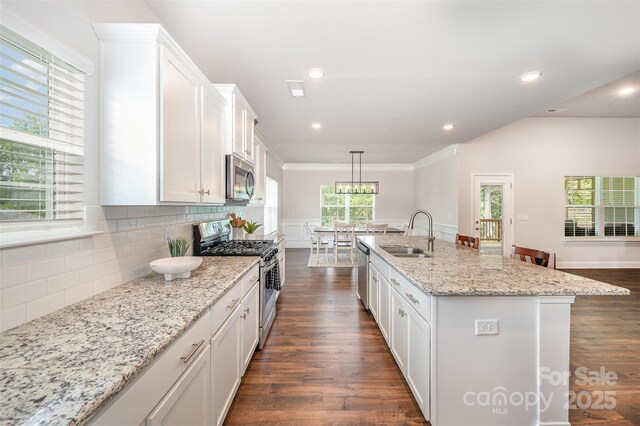 7739 Village Pkwy, Locust, NC 28097 - kitchen featuring stainless steel appliances, white cabinets, dark wood-type flooring, decorative backsplash, and a center island with sink