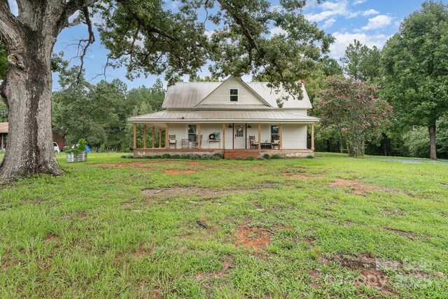 220 Low Water Bridge Rd, Troy, NC 27371 - farmhouse-style home featuring covered porch, a front lawn, and a metal roof