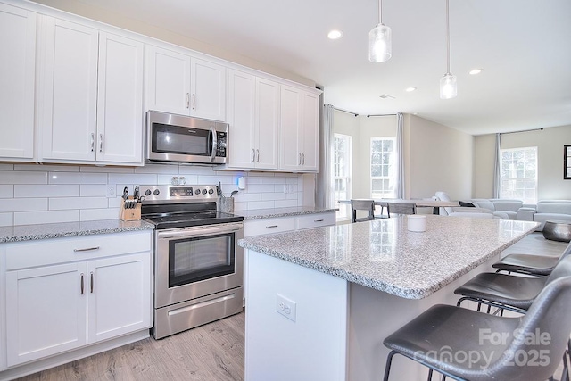 4017 Avis Way, Monroe, NC 28110 - kitchen with stainless steel appliances, light wood-style flooring, white cabinetry, decorative backsplash, and open floor plan