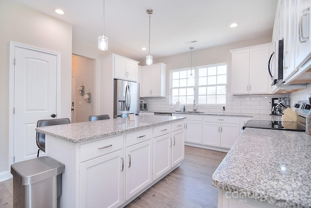 4017 Avis Way, Monroe, NC 28110 - kitchen with stainless steel appliances, backsplash, light wood-style floors, a center island, and white cabinetry