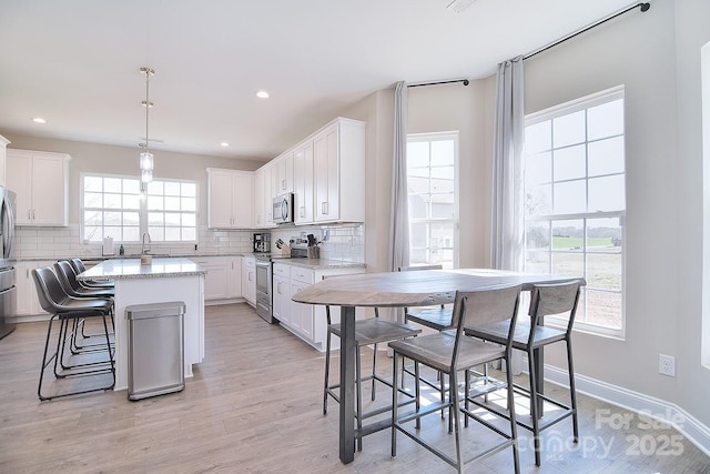 4017 Avis Way, Monroe, NC 28110 - kitchen with appliances with stainless steel finishes, decorative backsplash, a kitchen island, white cabinetry, and recessed lighting