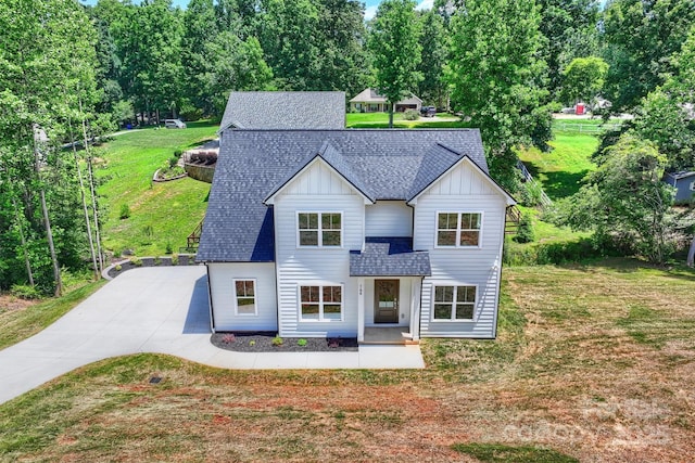 164 Meadow Glen Dr, Troutman, NC 28166 - view of front of house featuring board and batten siding, a front lawn, roof with shingles, concrete driveway, and view of scattered trees