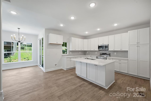 164 Meadow Glen Dr, Troutman, NC 28166 - kitchen with appliances with stainless steel finishes, wood finished floors, light countertops, a chandelier, and white cabinetry