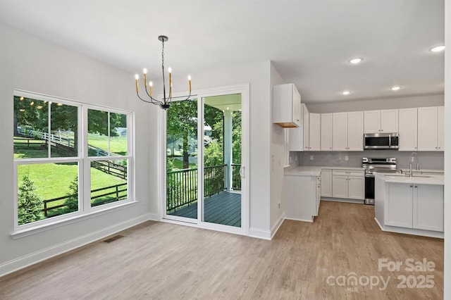 164 Meadow Glen Dr, Troutman, NC 28166 - kitchen featuring stainless steel appliances, light wood finished floors, healthy amount of natural light, a chandelier, and recessed lighting