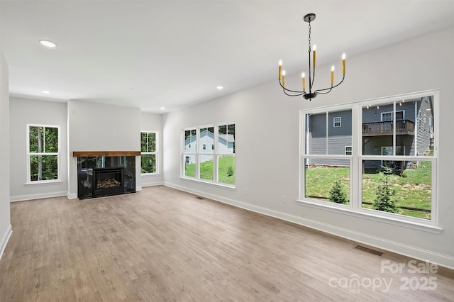 164 Meadow Glen Dr, Troutman, NC 28166 - unfurnished living room with a chandelier, plenty of natural light, wood finished floors, recessed lighting, and a premium fireplace
