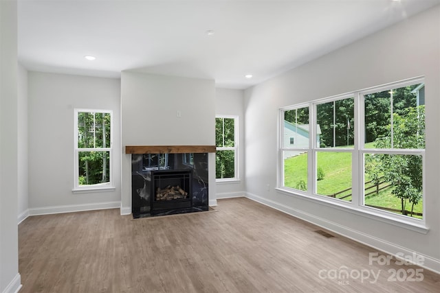 164 Meadow Glen Dr, Troutman, NC 28166 - unfurnished living room with wood finished floors, healthy amount of natural light, a premium fireplace, and recessed lighting