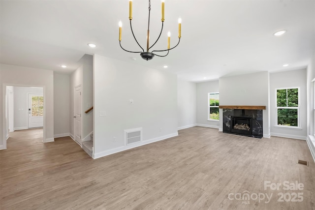 164 Meadow Glen Dr, Troutman, NC 28166 - unfurnished living room with plenty of natural light, light wood-style floors, a chandelier, recessed lighting, and a premium fireplace