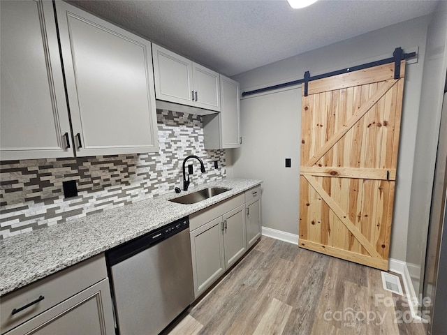 3824 Freedom Dr, Charlotte, NC 28208 - kitchen featuring dishwasher, light wood-style flooring, decorative backsplash, light stone counters, and a barn door