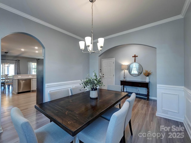 1324 Mona Vale Dr, Huntersville, NC 28078 - dining area featuring arched walkways, a chandelier, light wood-style flooring, a wainscoted wall, and crown molding