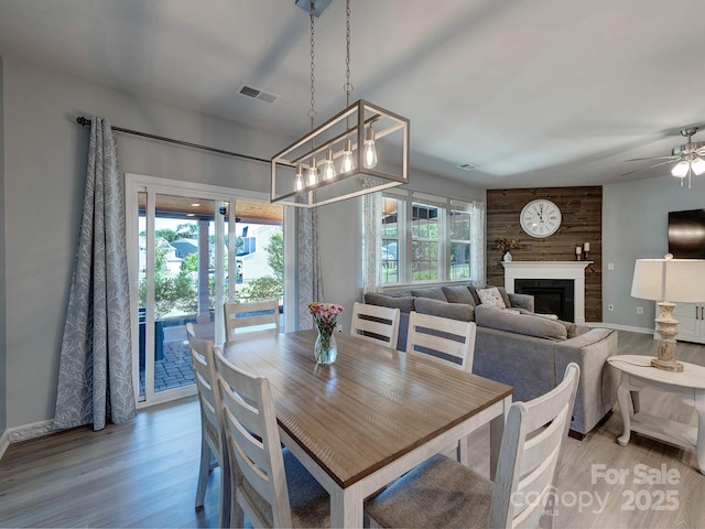 1324 Mona Vale Dr, Huntersville, NC 28078 - dining space featuring light wood finished floors, a ceiling fan, a glass covered fireplace, and a chandelier