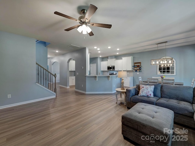 1324 Mona Vale Dr, Huntersville, NC 28078 - living room with arched walkways, a ceiling fan, wood finished floors, stairs, and recessed lighting