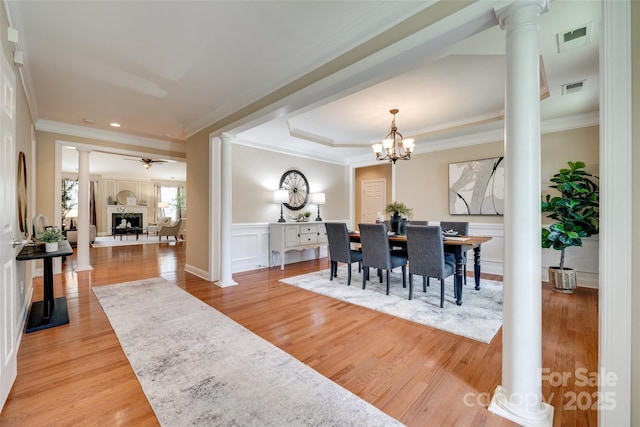 3905 Hounslow Ln, Harrisburg, NC 28075 - dining area with decorative columns, light wood-style floors, crown molding, a fireplace, and a chandelier