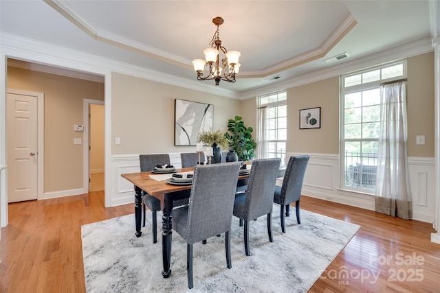 3905 Hounslow Ln, Harrisburg, NC 28075 - dining space with a chandelier, wainscoting, light wood finished floors, crown molding, and a raised ceiling