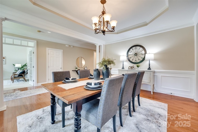 3905 Hounslow Ln, Harrisburg, NC 28075 - dining area featuring ornate columns, light wood-style floors, a chandelier, crown molding, and wainscoting