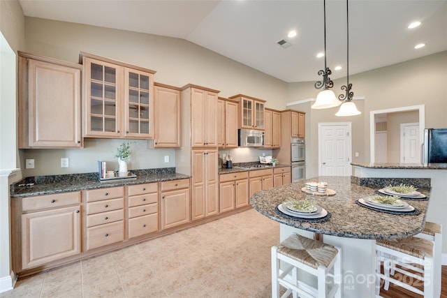 3905 Hounslow Ln, Harrisburg, NC 28075 - kitchen with stainless steel appliances, light brown cabinetry, a kitchen bar, vaulted ceiling, and recessed lighting