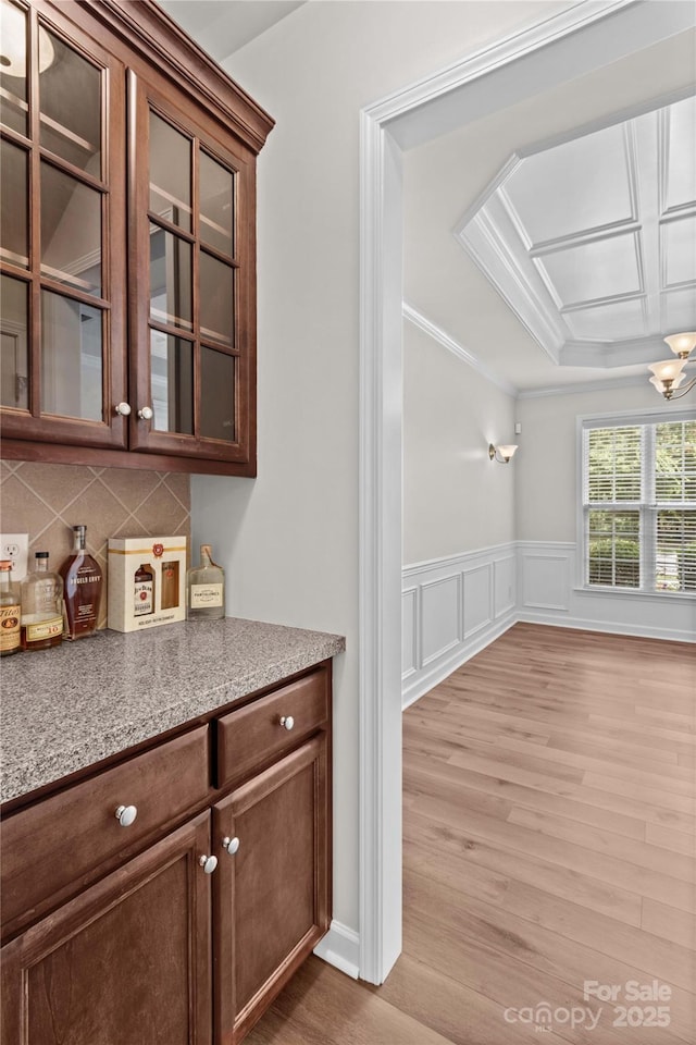 1011 Wadsworth Ln, Indian Trail, NC 28079 - bar area featuring light wood-style flooring, tasteful backsplash, crown molding, a chandelier, and a wainscoted wall
