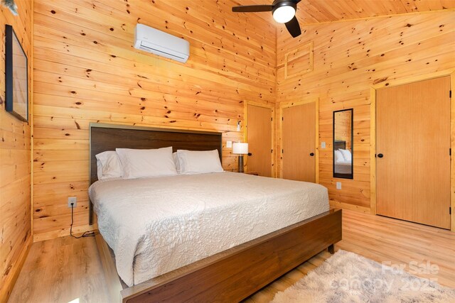 7025 Martin Ln, Morganton, NC 28655 - bedroom with a wall mounted AC, a towering ceiling, wood walls, light wood-style flooring, and ceiling fan