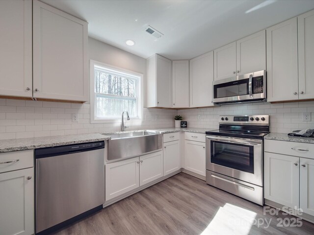 1016 Forest Dr, Marshville, NC 28103 - kitchen with appliances with stainless steel finishes, white cabinetry, light wood-style floors, decorative backsplash, and recessed lighting