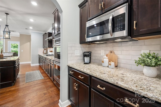 1805 Trading Path Ln, Waxhaw, NC 28173 - kitchen with appliances with stainless steel finishes, ornamental molding, light wood-type flooring, dark brown cabinetry, and decorative backsplash