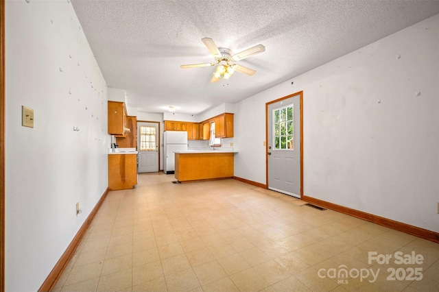 49 Meadowbrook Rd, Rutherfordton, NC 28139 - kitchen with freestanding refrigerator, plenty of natural light, light countertops, brown cabinetry, and a textured ceiling