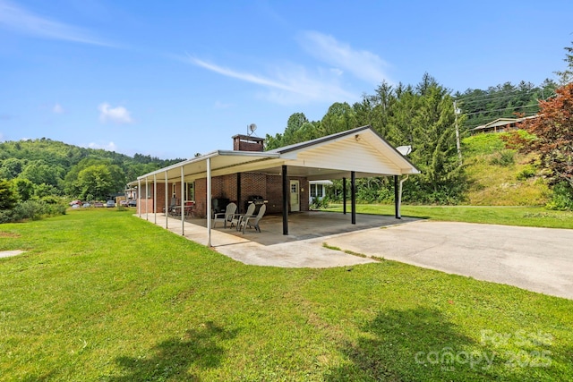 100 Nimitz Dr, Brevard, NC 28712 - back of house featuring a lawn, a patio area, concrete driveway, brick siding, and a chimney