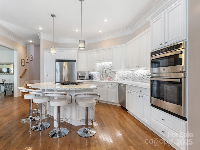8918 Cotton Press Rd, Charlotte, NC 28277 - kitchen featuring stainless steel appliances, white cabinets, a kitchen island, a kitchen breakfast bar, and decorative backsplash
